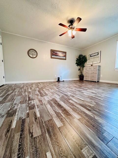 unfurnished living room featuring a textured ceiling, ceiling fan, ornamental molding, and wood-type flooring