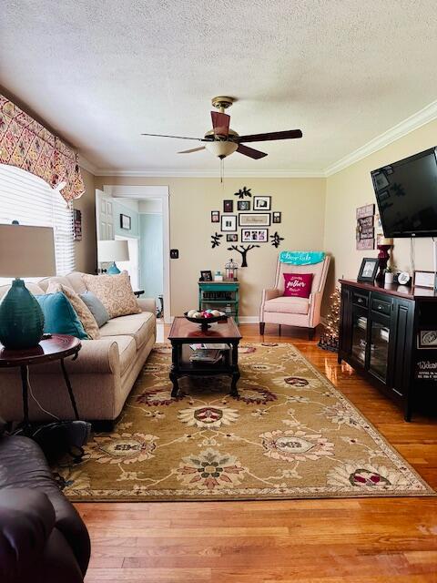 living room featuring crown molding, a textured ceiling, hardwood / wood-style floors, and ceiling fan