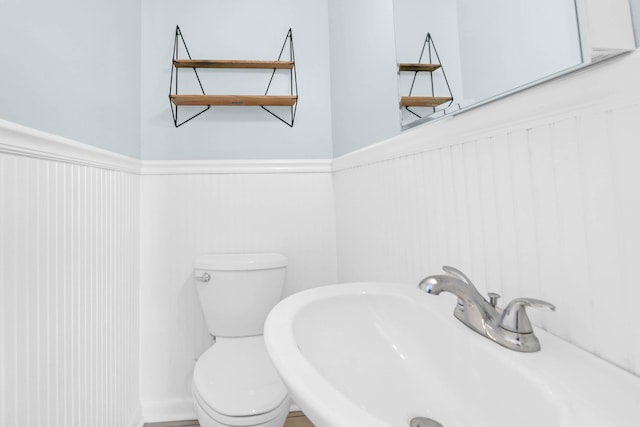 bathroom with a sink, a wainscoted wall, and toilet