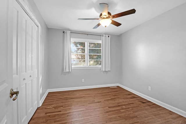 unfurnished bedroom featuring visible vents, baseboards, wood finished floors, a closet, and a ceiling fan