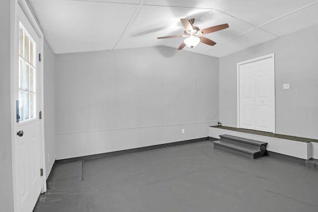 empty room featuring vaulted ceiling, a ceiling fan, and concrete flooring