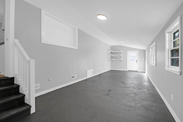 unfurnished living room with visible vents, lofted ceiling, baseboards, concrete flooring, and stairs