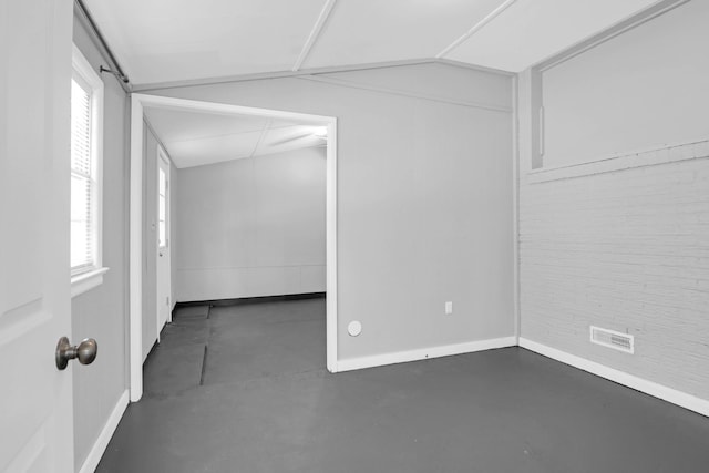 unfurnished room featuring baseboards, lofted ceiling, concrete flooring, and a healthy amount of sunlight