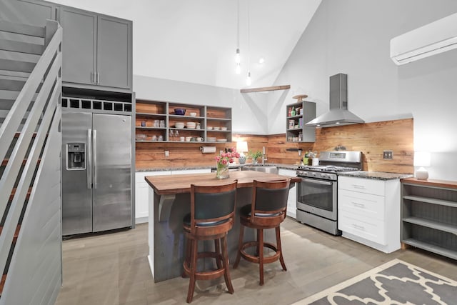 kitchen featuring an AC wall unit, open shelves, appliances with stainless steel finishes, wall chimney exhaust hood, and wooden counters