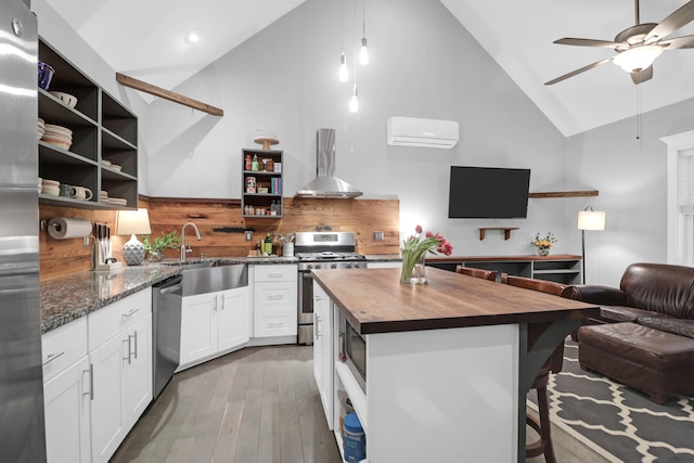 kitchen featuring open shelves, ventilation hood, butcher block counters, stainless steel appliances, and a sink