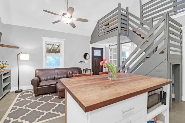 interior space with baseboards, lofted ceiling, a ceiling fan, and stairs