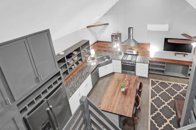 kitchen featuring open shelves, oven, wood finished floors, wall chimney exhaust hood, and a sink