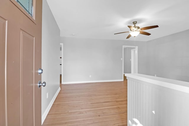 spare room with ceiling fan, light wood-type flooring, and baseboards