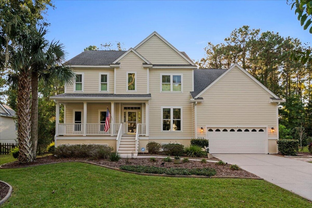 view of front of property featuring a garage, covered porch, and a front yard