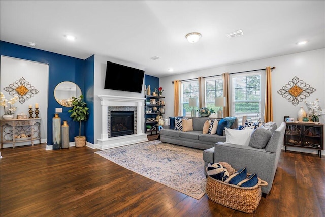 living area with visible vents, baseboards, wood finished floors, and a tiled fireplace