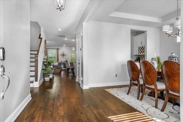 dining space with visible vents, dark wood-type flooring, baseboards, a chandelier, and stairs