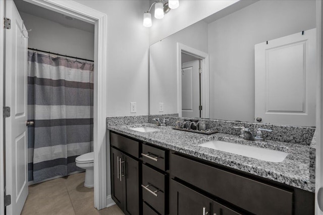 bathroom featuring tile patterned flooring, double vanity, toilet, and a sink