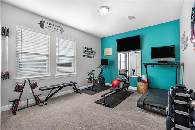 exercise area with visible vents, baseboards, and carpet