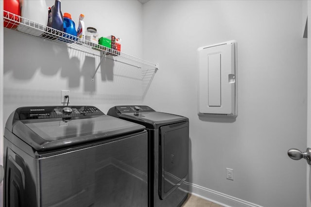 washroom featuring electric panel, baseboards, laundry area, and washing machine and clothes dryer