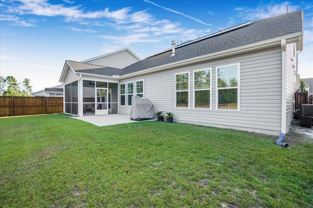 back of house with a lawn, fence, a sunroom, and roof with shingles