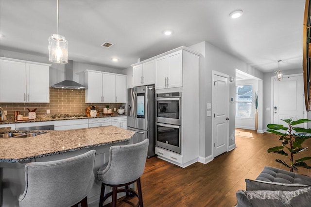 kitchen with a sink, decorative backsplash, wall chimney exhaust hood, and stainless steel appliances