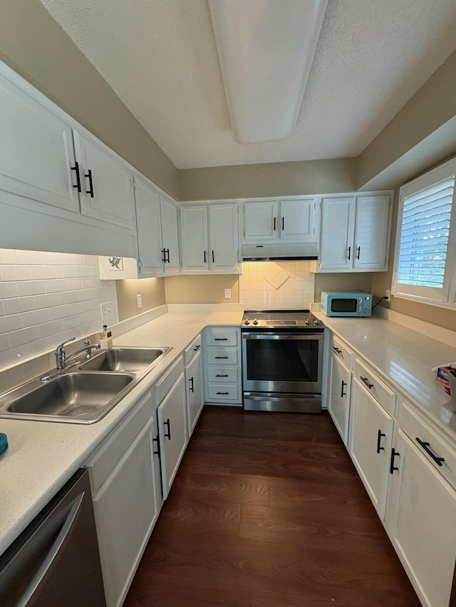 kitchen with appliances with stainless steel finishes, dark hardwood / wood-style flooring, a textured ceiling, sink, and white cabinetry