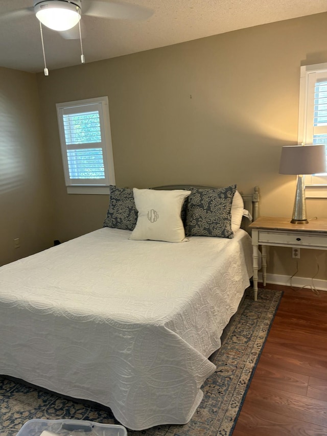 bedroom with ceiling fan, dark hardwood / wood-style flooring, and a textured ceiling