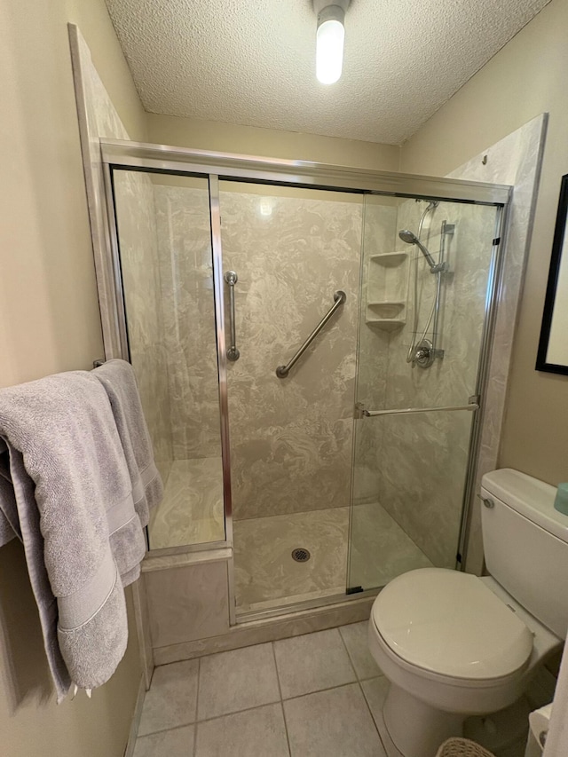 bathroom featuring a textured ceiling, tile patterned flooring, an enclosed shower, and toilet