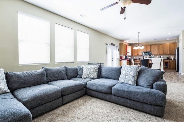 living room with recessed lighting, light carpet, and ceiling fan with notable chandelier