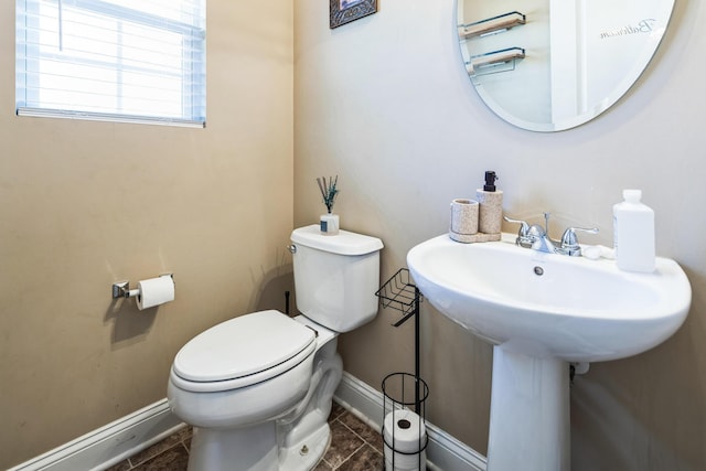 bathroom with tile patterned floors, toilet, baseboards, and a sink