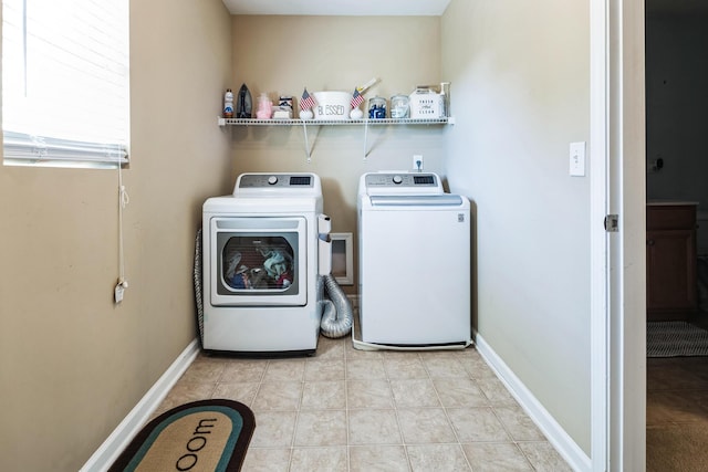 clothes washing area featuring light tile patterned floors, baseboards, separate washer and dryer, and laundry area