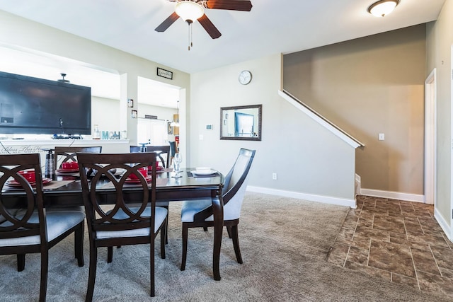 dining space with stone finish floor, a ceiling fan, baseboards, and carpet floors