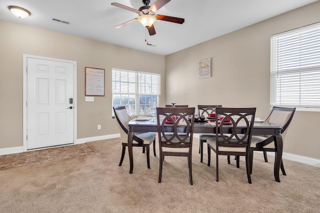 carpeted dining space with visible vents, baseboards, and ceiling fan