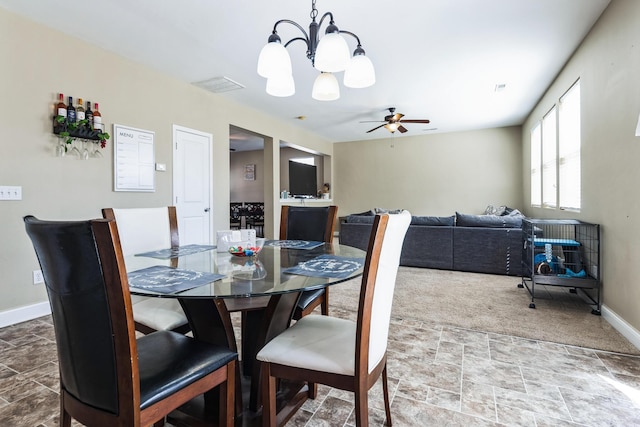 dining space with ceiling fan with notable chandelier, stone finish floor, visible vents, and baseboards