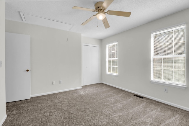 carpeted empty room featuring ceiling fan, a textured ceiling, and a wealth of natural light