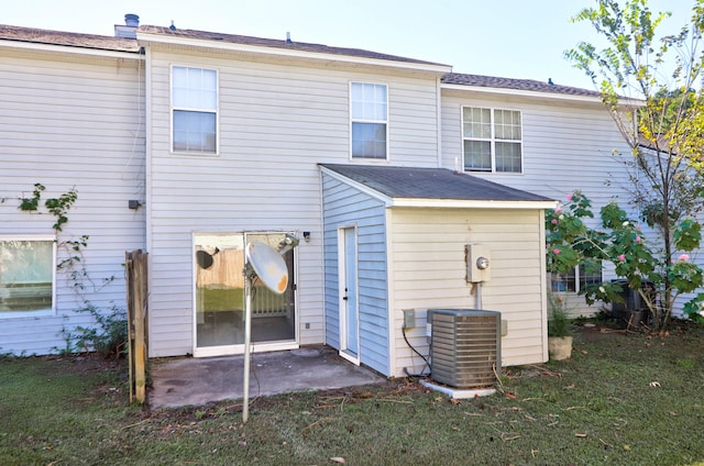 rear view of property featuring central AC unit, a lawn, and a patio