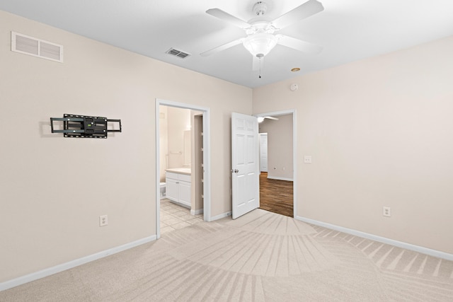 unfurnished bedroom featuring ceiling fan, light colored carpet, and ensuite bathroom