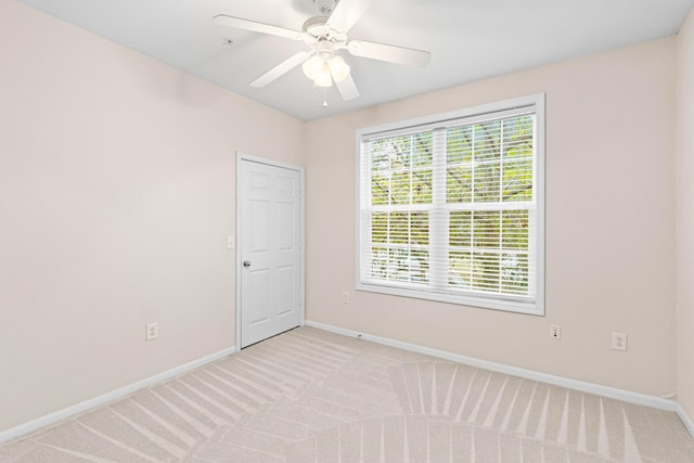 carpeted spare room featuring ceiling fan