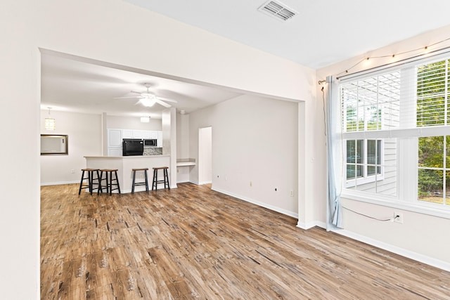 unfurnished living room featuring light hardwood / wood-style floors, ceiling fan, and a healthy amount of sunlight