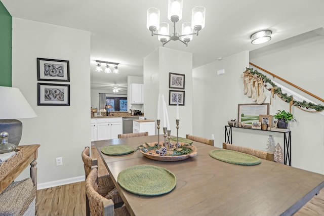 dining space featuring ceiling fan with notable chandelier, light hardwood / wood-style flooring, and sink