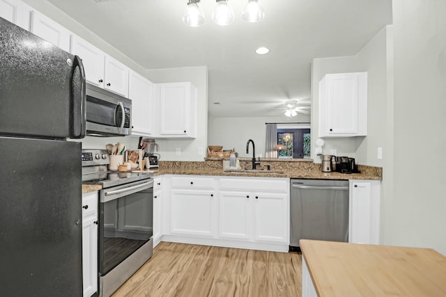 kitchen featuring white cabinets, stainless steel appliances, dark stone countertops, and sink