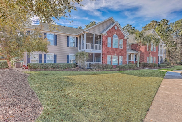 view of front of house with brick siding, a sunroom, and a front yard