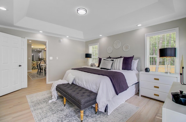 bedroom with recessed lighting, ornamental molding, a raised ceiling, and light wood-style floors