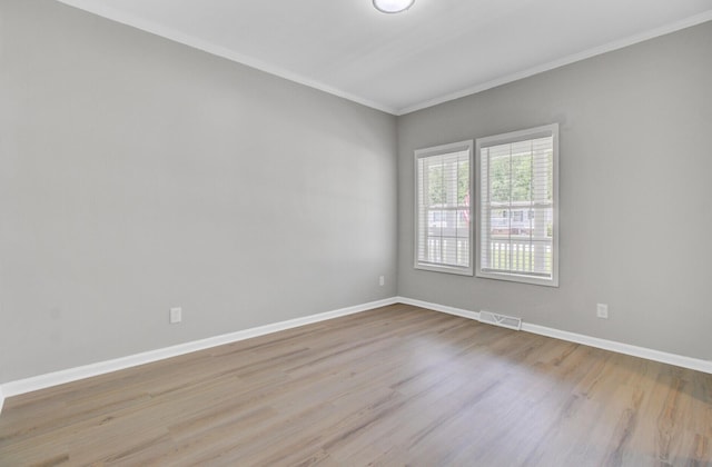 unfurnished room with visible vents, ornamental molding, baseboards, and wood finished floors