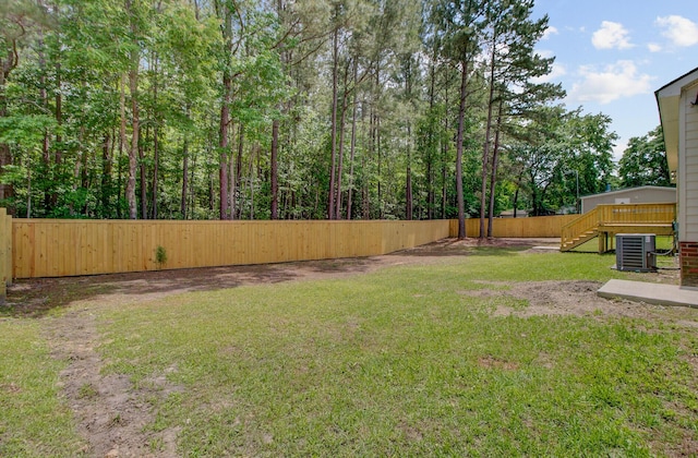 view of yard featuring central AC, stairway, and fence
