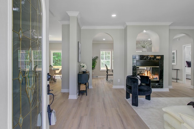 living room featuring arched walkways, light wood finished floors, a multi sided fireplace, and ornamental molding