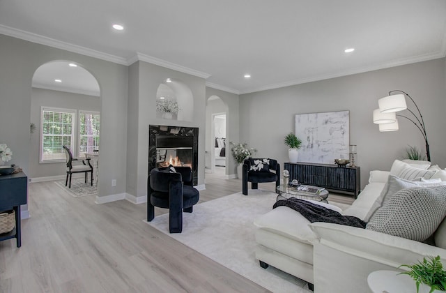 living room with crown molding, arched walkways, recessed lighting, and light wood-style flooring