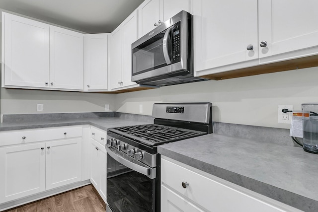 kitchen featuring light wood finished floors, white cabinetry, and appliances with stainless steel finishes