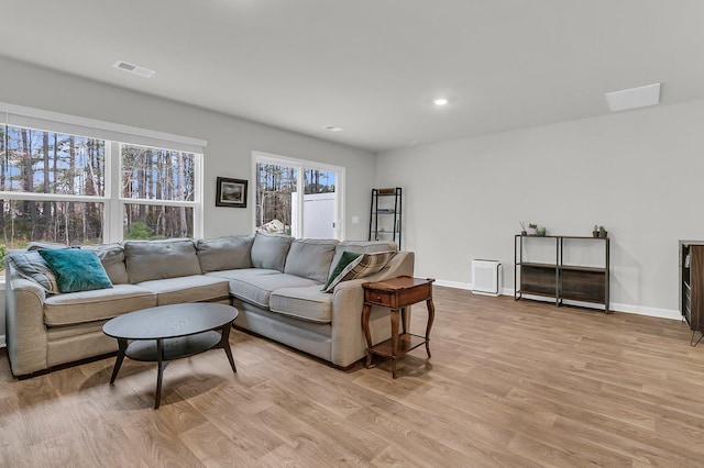 living room with light wood-style flooring, visible vents, baseboards, and recessed lighting