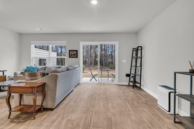 living area with light wood-style flooring, visible vents, and baseboards