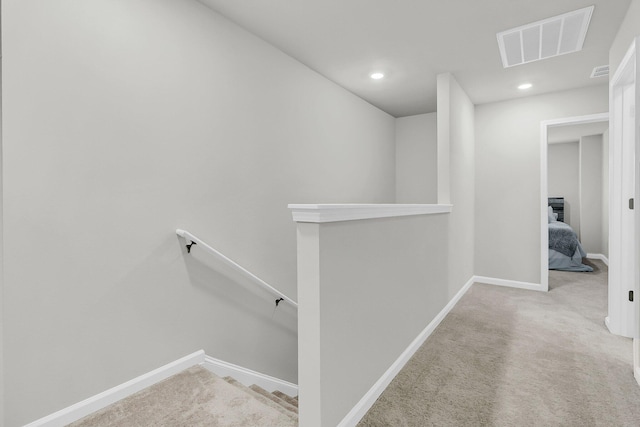 hall featuring baseboards, visible vents, carpet flooring, and an upstairs landing