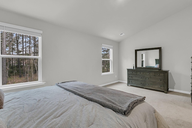 carpeted bedroom with lofted ceiling, visible vents, and baseboards