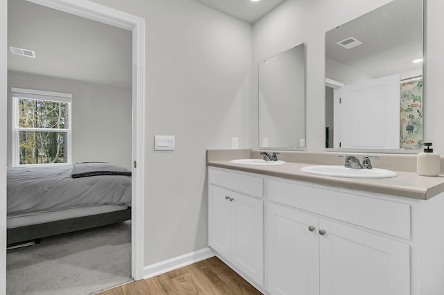 bathroom with connected bathroom, visible vents, a sink, and wood finished floors