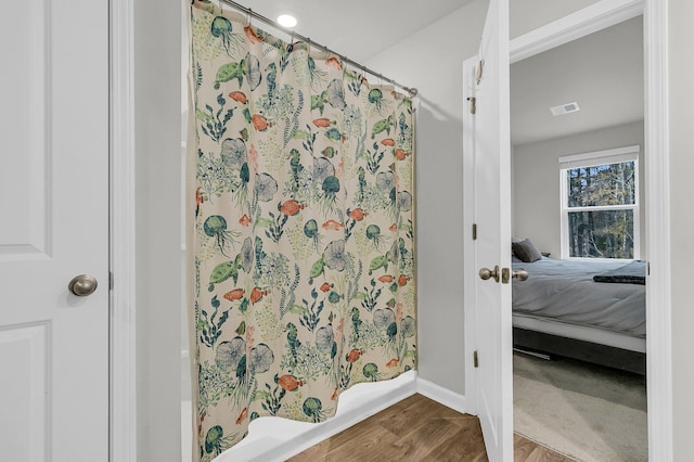 full bath featuring a shower with curtain, visible vents, ensuite bath, and wood finished floors