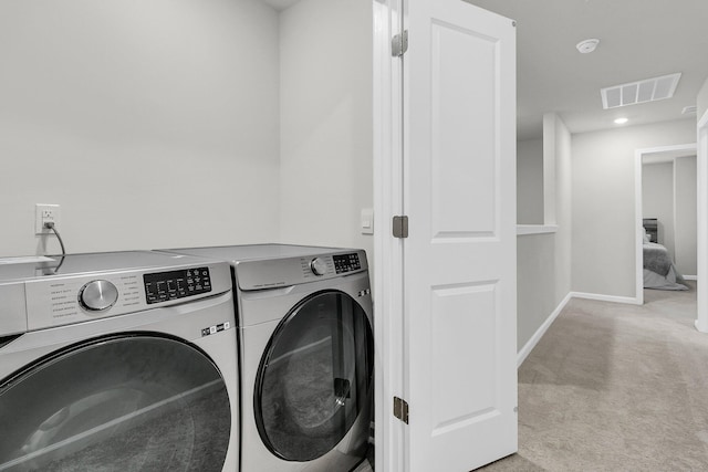 laundry area featuring light colored carpet, laundry area, visible vents, baseboards, and washer and clothes dryer